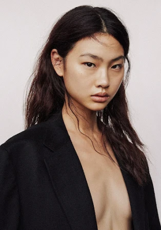 Portrait of an East Asian woman with dark hair wearing a black jacket against a plain background