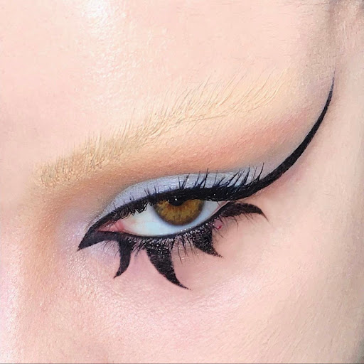 Close-up eye makeup portrait featuring dramatic winged black eyeliner and bleached eyebrows by Manuela Balducci
