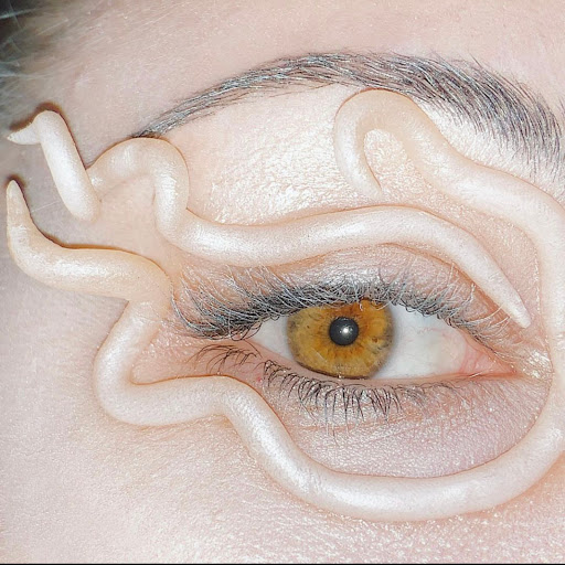 Close-up of a person's eye with decorative white squiggles around it as fashion makeup to draw attention to the eye.
