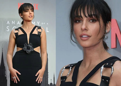 Naomi Scott poses in a stylish black cut-out dress with flower detail and silver hardware on the red carpet at a movie premiere.