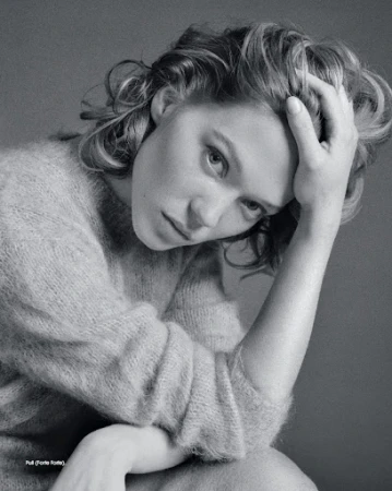 Black and white portrait of a woman with her hand on her head, wearing a soft textured sweater, gazing at the camera.