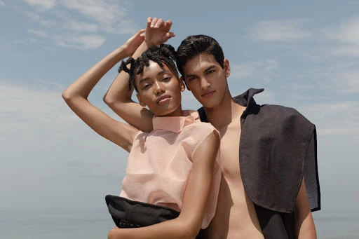 Portrait of a Black woman with braided hair and a man standing together outdoors against an open blue sky