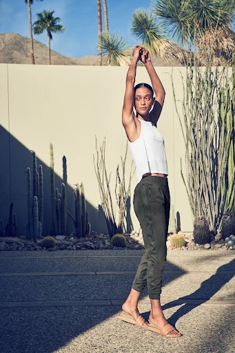 Athletic woman in sportswear standing in desert landscape with neutral background, bathed in natural light; fitness and fashion imagery.