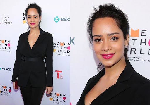 Elegant adult woman in a black belted blazer posing at a 'Women in the World' event, showcasing fashion and event photography in an indoor setting.