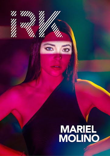 Portrait of woman in one-shoulder dress, lit with pink and yellow gels, against a dark background with the text, IRK, Mariel Molino.