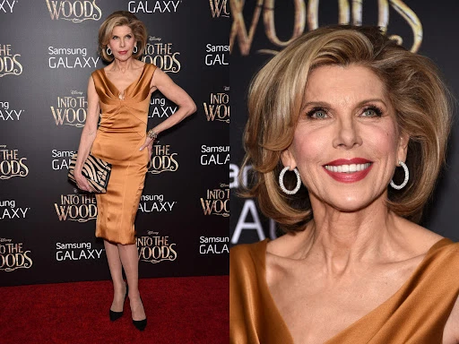 Christine Baranski poses on the red carpet in a gold dress and black heels in front of a movie advertisement backdrop.