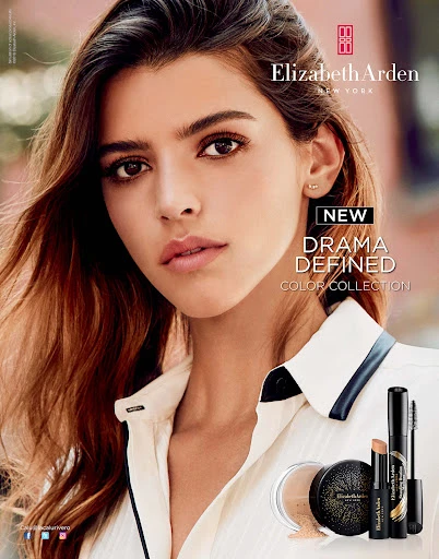 Close-up beauty shot of a fair-skinned woman with dark brown hair wearing a white collared shirt, promoting Elizabeth Arden makeup.