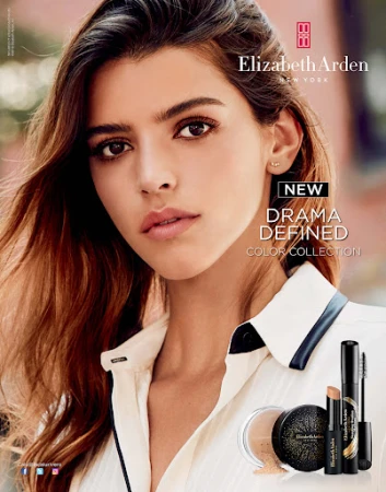 Close-up beauty shot of a fair-skinned woman with dark brown hair wearing a white collared shirt, promoting Elizabeth Arden makeup.