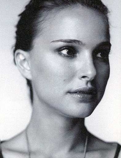 Black and white portrait of a woman with dark hair and eyes, looking to the side, wearing a necklace, against a light gray background.