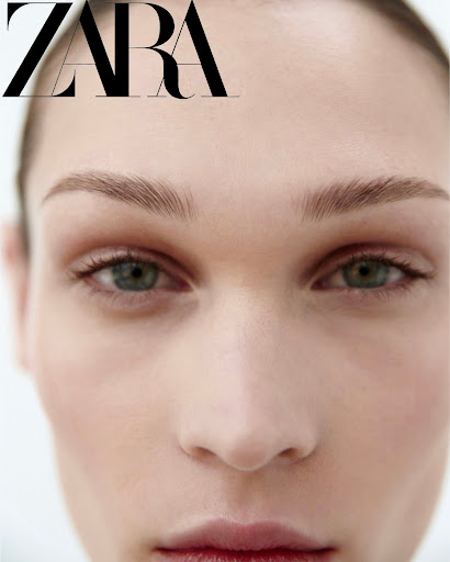 Close-up beauty portrait of a model with natural makeup and dark green eyes against a white background.