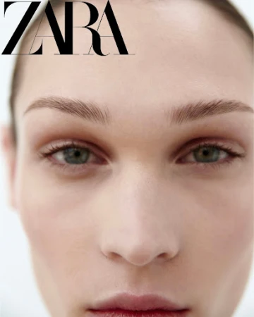 Close-up beauty portrait of a model with natural makeup and dark green eyes against a white background.