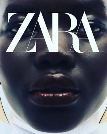 Close-up portrait of a model with dark skin and glossy lips wearing a white turtleneck and gold earrings, styled by Sohphea.