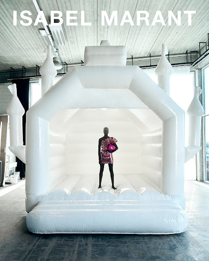 Fashion shot featuring a slender model in a glittering dress, posing inside a pristine white inflatable bounce house, with the brand name above.
