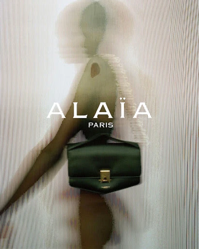 Alaïa handbag featured in a fashion advertisement, showcasing a green leather bag against a textured background with the brand logo.