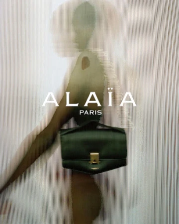 Alaïa handbag featured in a fashion advertisement, showcasing a green leather bag against a textured background with the brand logo.