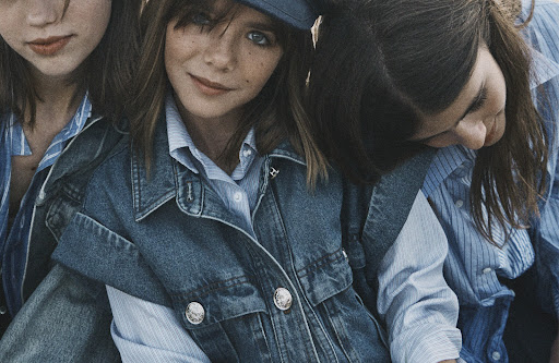 Three young people in a close-up shot wearing blue denim and striped shirts, creating a fashionable and coordinated aesthetic.