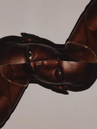 Close-up portrait of a Black man with a gold chain necklace featuring torn paper collage effect against a light grey background