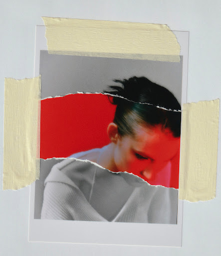 Torn photo of a woman with red lighting, taped to a white surface. Focus on the woman, the paper tear, and tape.