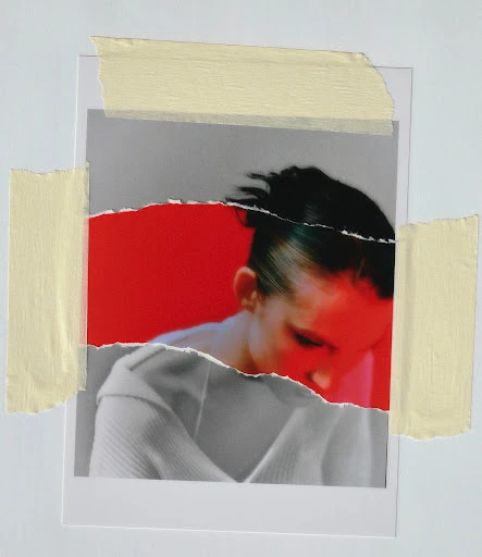Torn photo of a woman with red lighting, taped to a white surface. Focus on the woman, the paper tear, and tape.