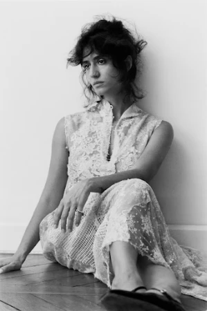 Monochrome portrait of a woman in a lace dress seated against a wall in Paris