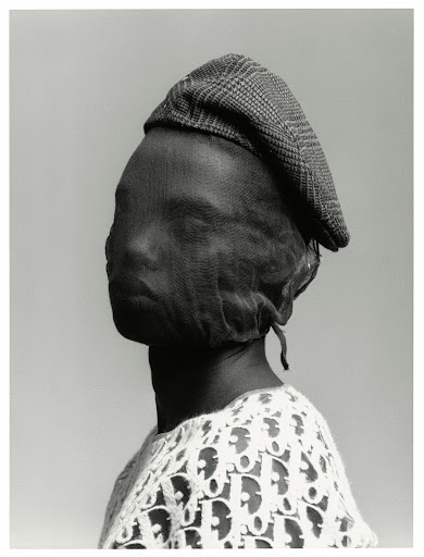 Monochrome portrait of a person wearing a plaid driving cap and a sheer fabric over their face, with a Dior logo shirt.