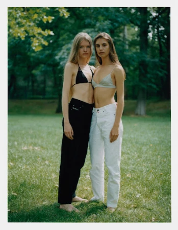 Two female models standing in a park wearing bralettes and trousers, makeup by Victoria Reuter.