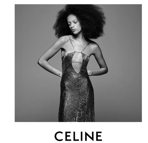 Black and white portrait of an African American woman in a sparkling, cut-out dress posing in front of a neutral background. Fashion editorial.