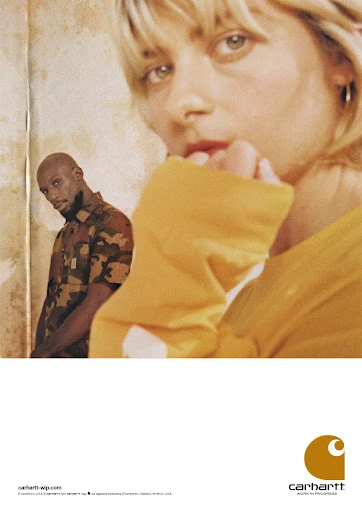 Fashion advertisement featuring two people; an adult woman with blond hair, wearing a yellow top, and an adult man in a camo shirt.