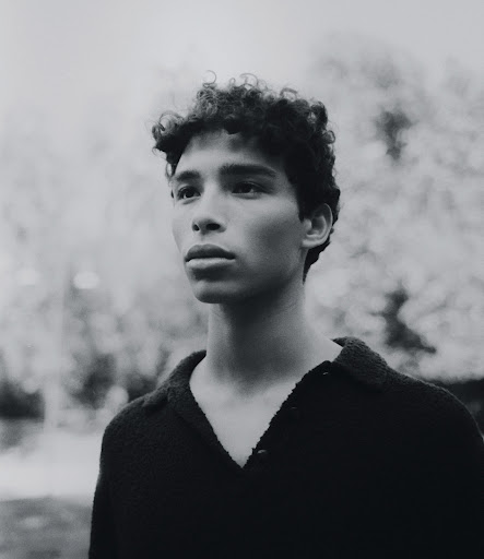 Adult male model poses in grey suit, captured in a photo studio, using artificial lighting and against a neutral backdrop.
