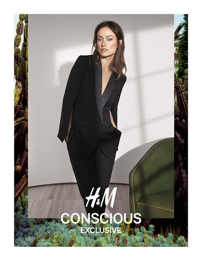 Olivia Wilde wearing a black blazer and trousers in an indoor studio setting framed by a border of cacti.