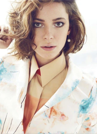 Close-up portrait of a woman with short brown hair wearing a patterned jacket and collared shirt, by Ben Skervin