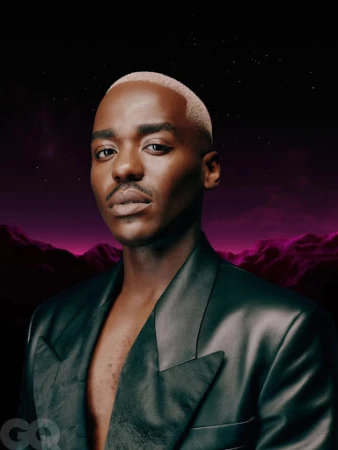 Portrait of Black male adult in black leather jacket, styled with short bleached hair, against a digital landscape background. GQ logo visible.