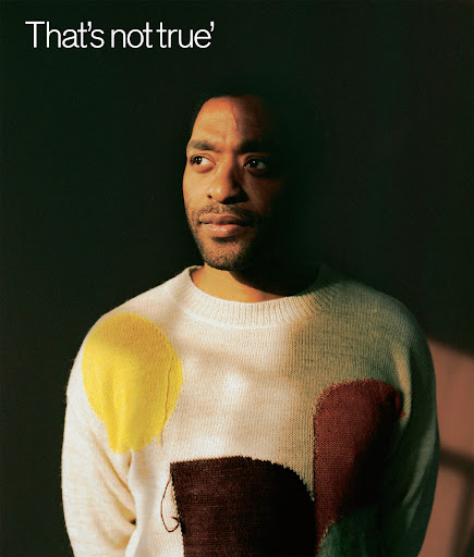Portrait of a Black adult male in a cream sweater with abstract shapes, looking off to the side against a dark green background.