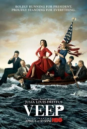 Julia Louis-Dreyfus in a red dress standing in a rowboat with several other people on choppy ocean waters.