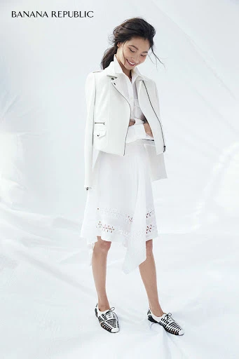 Asian woman in white jacket and eyelet dress posing in bright studio light. Banana Republic logo in upper left corner.