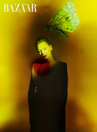 A woman in a black outfit poses with a large moth against a textured yellow background in a fashion editorial image. 