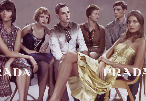 Group of six fashion models posing in vintage clothing with large Prada text overlaid across the foreground.