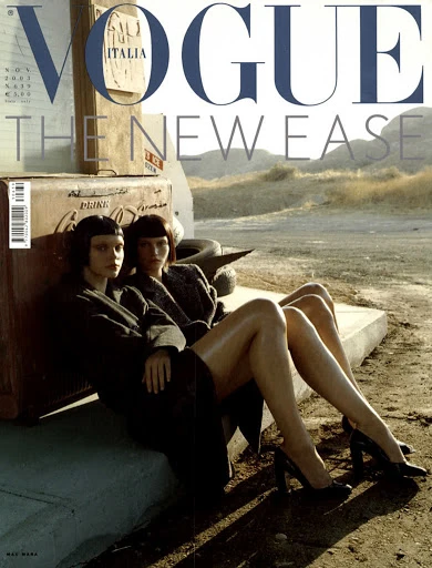 Vogue Italia cover featuring two models in coats and heels, posing in a desert landscape near a Coca-Cola cooler and old tires.
