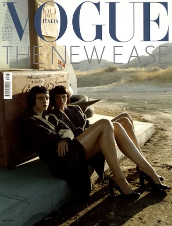 Vogue Italia cover featuring two models in coats and heels, posing in a desert landscape near a Coca-Cola cooler and old tires.