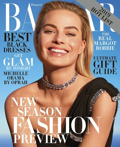 Magazine cover of Harper's Bazaar featuring Margot Robbie smiling with blonde hair and a black dress with blue accents and jewelry.