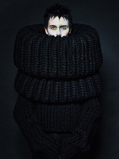 Model wearing an oversized chunky black knit sweater with a massive ribbed cowl neck framing the face, styled by Kabuto Okuzawa.