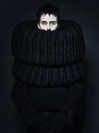 Model wearing an oversized chunky black knit sweater with a massive ribbed cowl neck framing the face, styled by Kabuto Okuzawa.