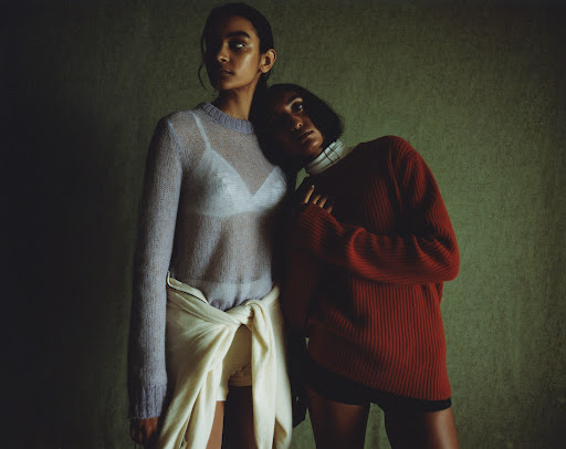 Two women posing together against a textured green background with hair styled by Kelly Peach.