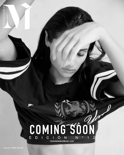 Black-and-white fashion magazine cover featuring a woman with long hair wearing a dark t-shirt, covering her face with her hand.