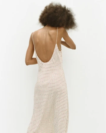 Model with afro hair seen from behind wearing a patterned slip dress against a white background