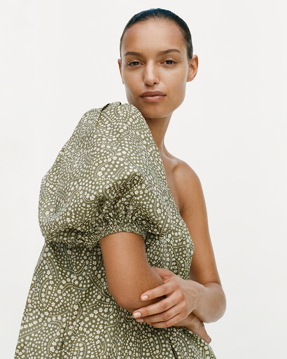 Woman in green patterned puff sleeve dress against white background. Fashion, portrait, indoor studio shot of model wearing dress.