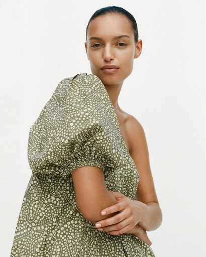Woman in green patterned puff sleeve dress against white background. Fashion, portrait, indoor studio shot of model wearing dress.