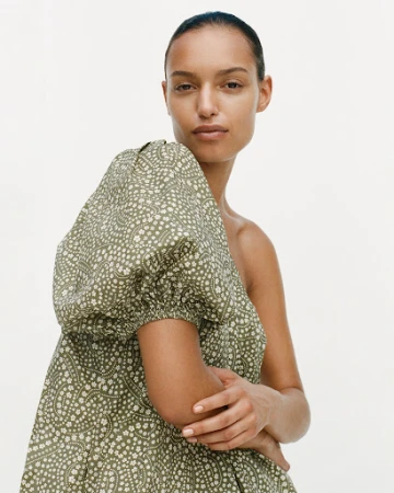 Woman in green patterned puff sleeve dress against white background. Fashion, portrait, indoor studio shot of model wearing dress.