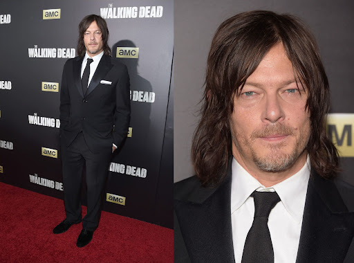 Norman Reedus in a dark suit at the premiere of The Walking Dead. He is standing against a backdrop with the show's logo.