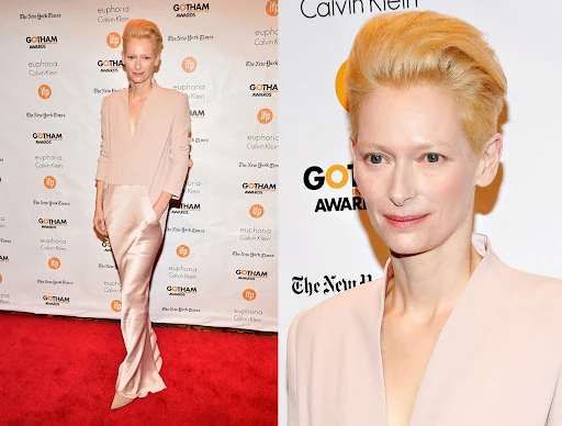 Blonde woman poses in front of awards backdrops on a red carpet in a beige outfit at an entertainment event. Headshot also included.